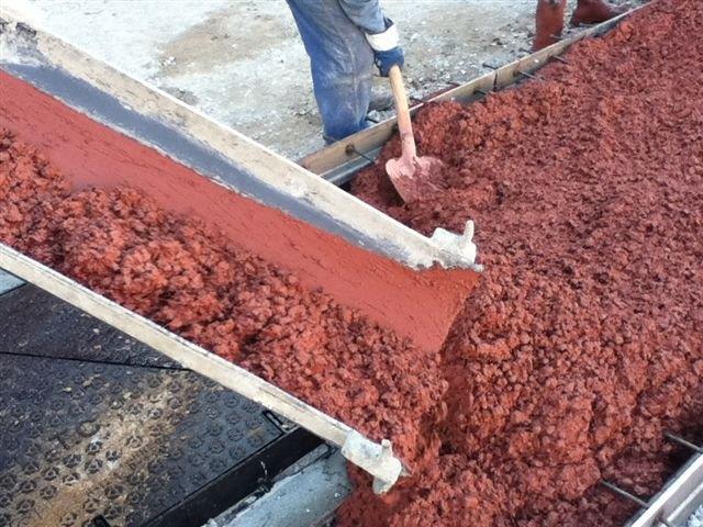 Operarios vierten hormigón coloreado en la construcción de un camino.