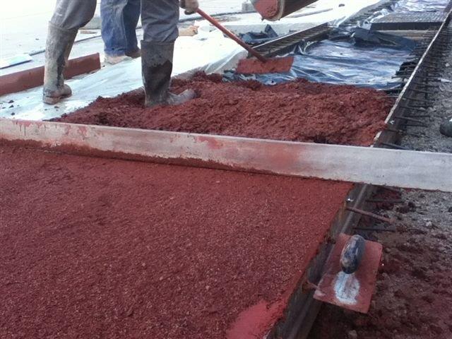 Operarios reparten el hormigón coloreado en la construcción de un camino.