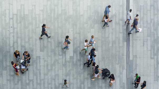 Imagen cenital de personas andando en una calle con el suelo gris hormigón
