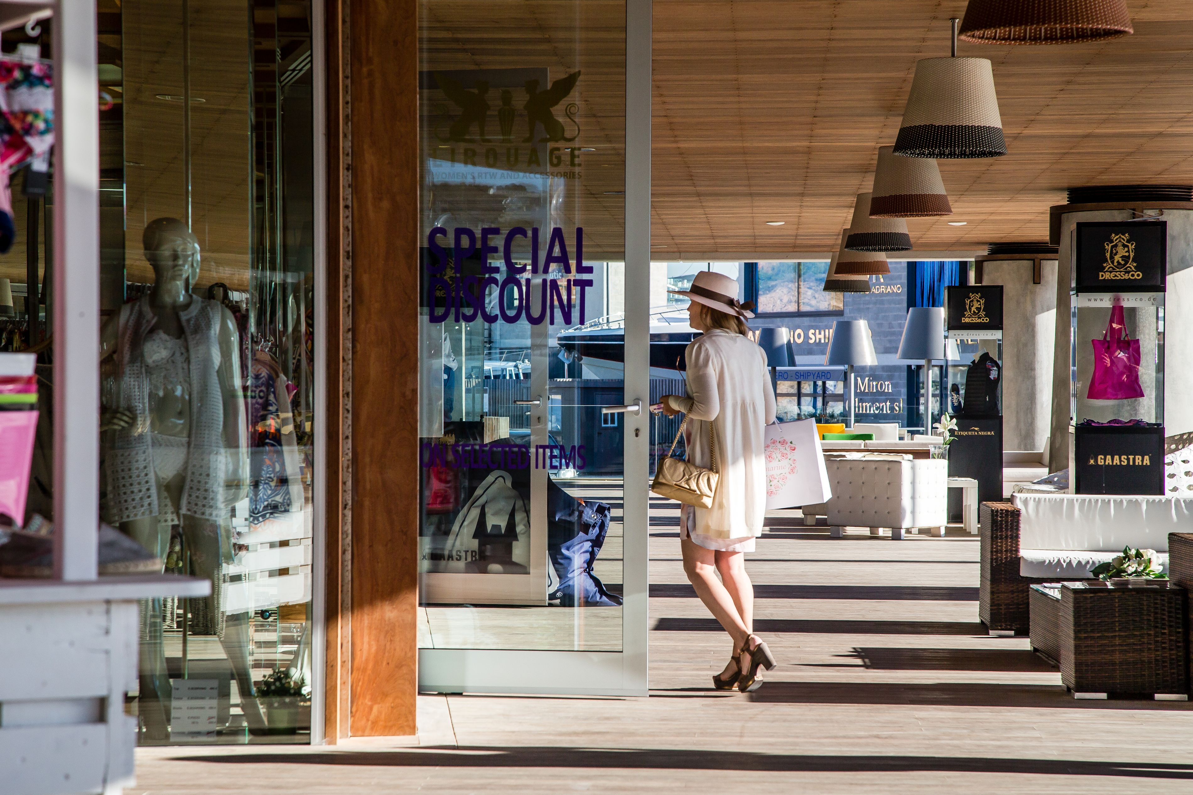 Mujer elegante mira los escaparates en las tiendas de lujo de Port Adriano